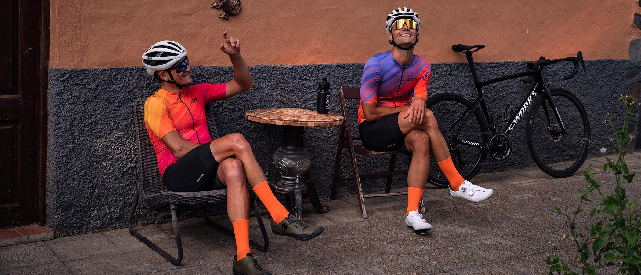 Zwei Radfahrer in hellorangefarbenen Luxa-Radbekleidungen